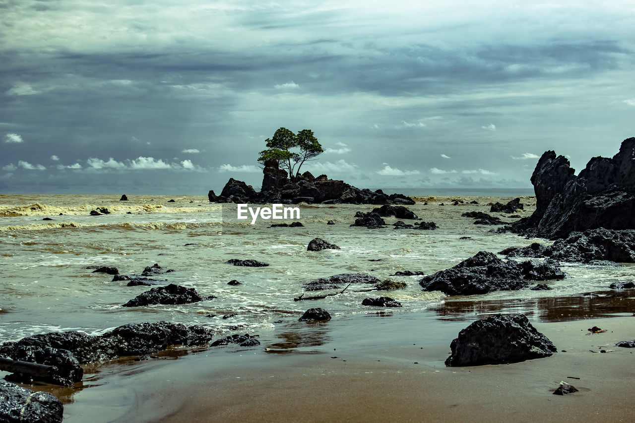 Rock formation on beach against sky