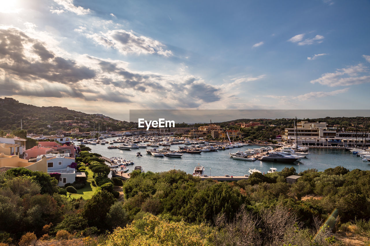 Sailboats moored in sea by town against sky