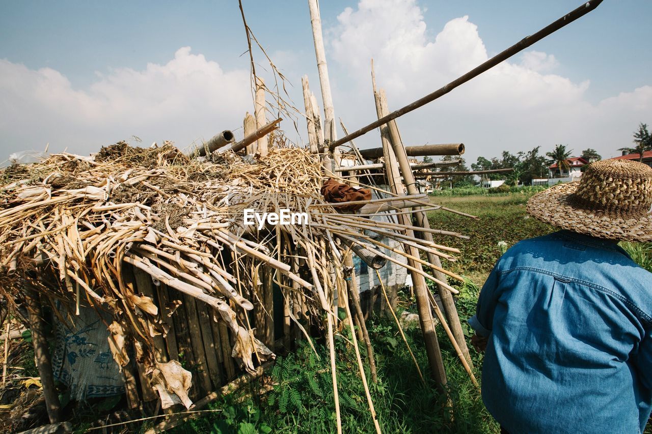 Rear view of person standing by hut on farm