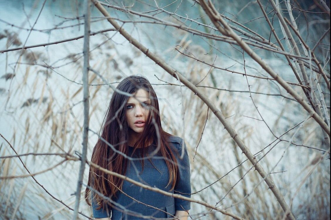 PORTRAIT OF YOUNG WOMAN STANDING IN PARK