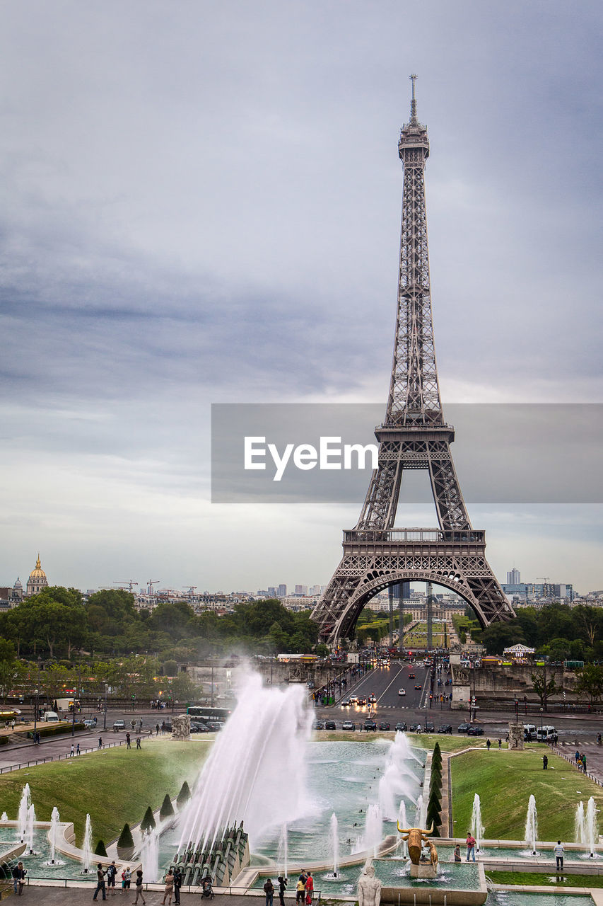 Eiffel tower on paris with a gray sky and a fountain in front