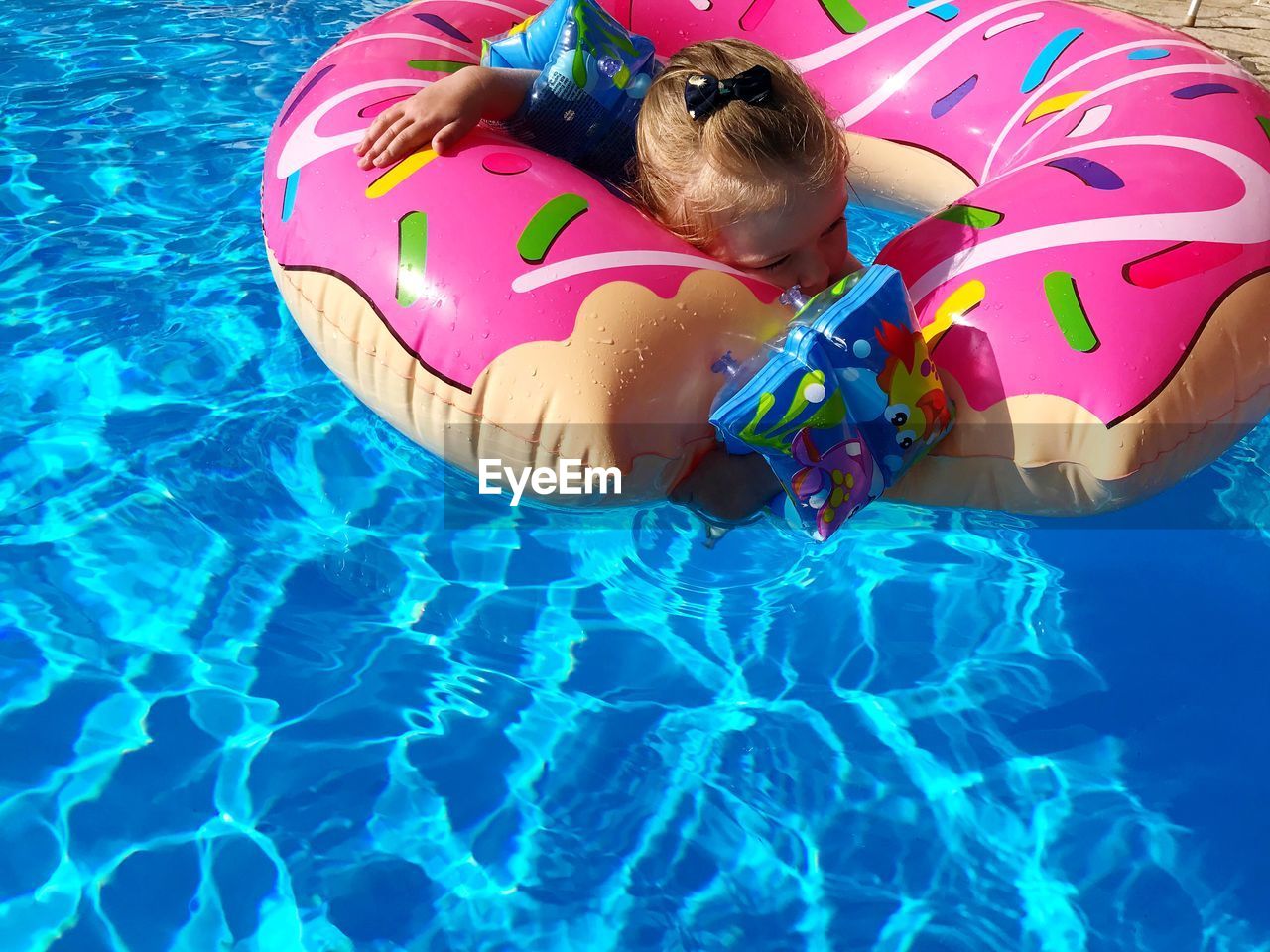 High angle view of girl floating in swimming pool with inflatable ring
