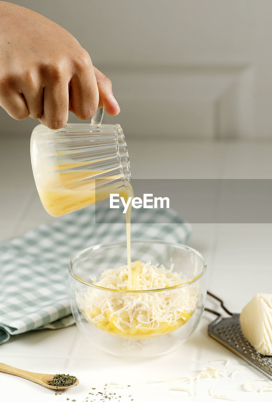 Pour condensed milk to the bowl with buttered cheese corn or jagung susu keju, on white table
