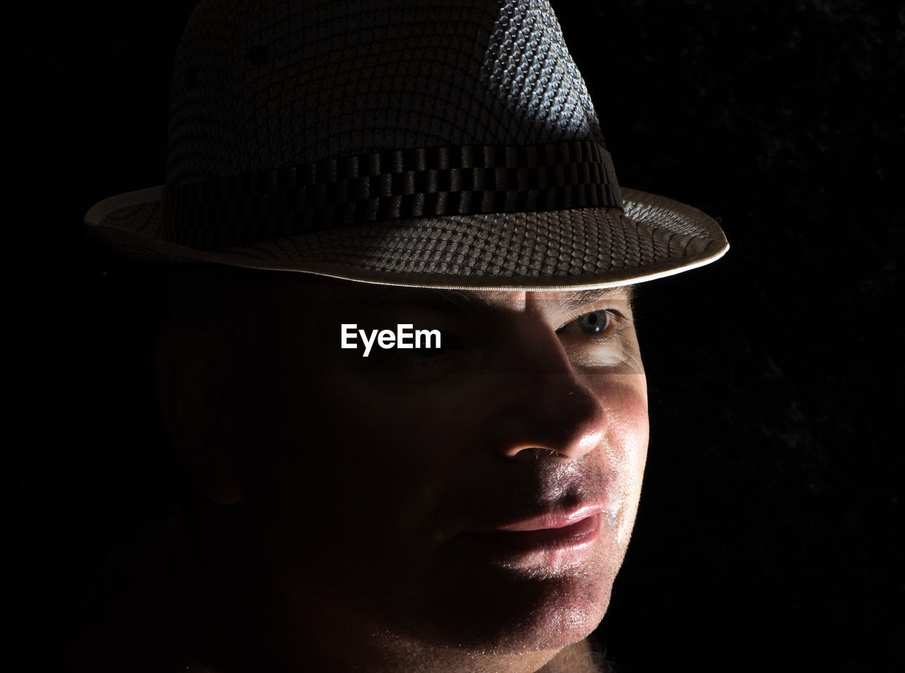 Close-up of man wearing hat in darkroom