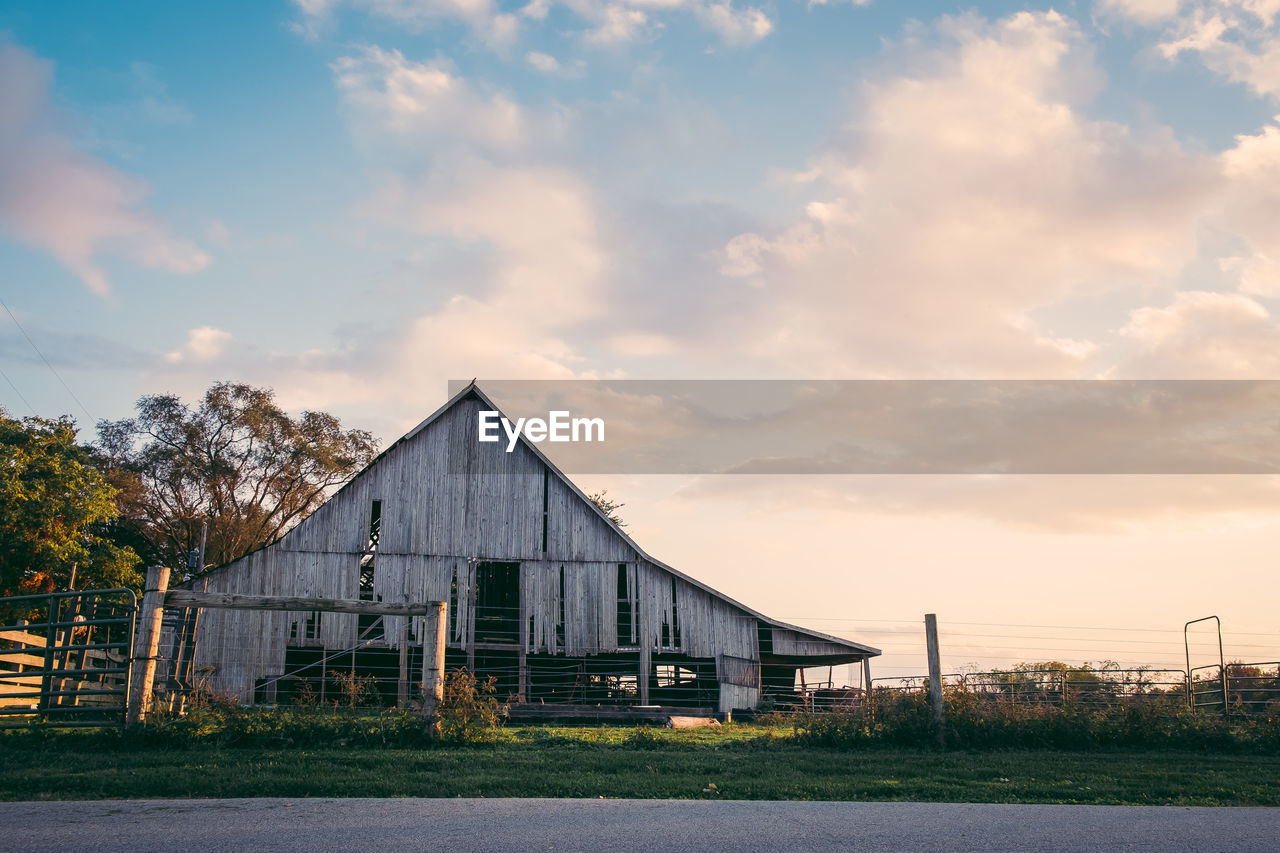 Barn on field against sky during sunset