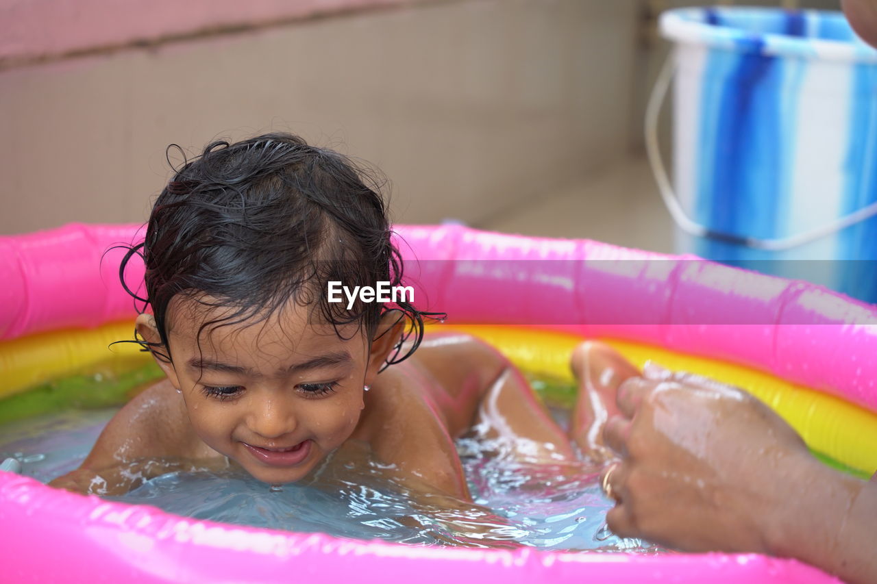 PORTRAIT OF CUTE GIRL WITH SWIMMING POOL IN WATER