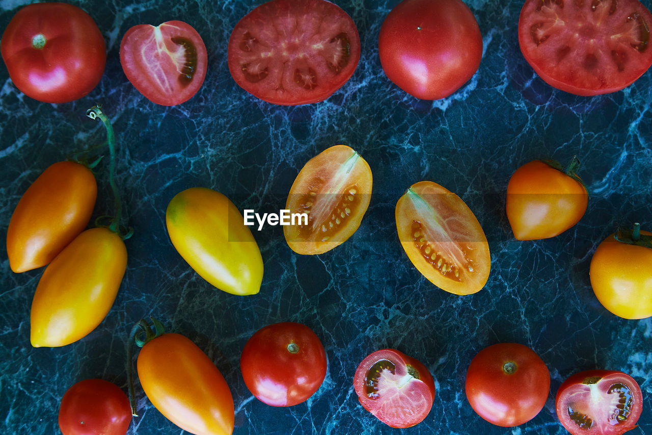 Autumn vegetables. colorful red, orange and yellow tomatoes on green marble background. 