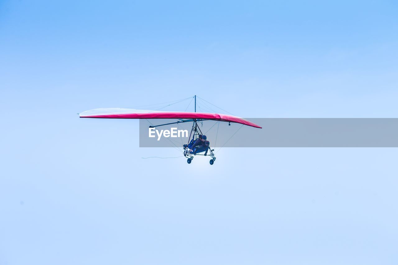 Low angle view of people hang gliding in sky