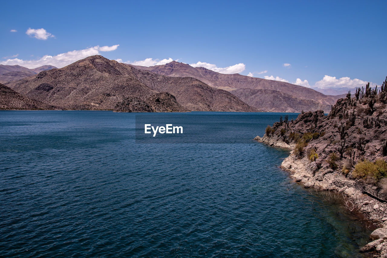 Scenic view of sea and mountains against blue sky