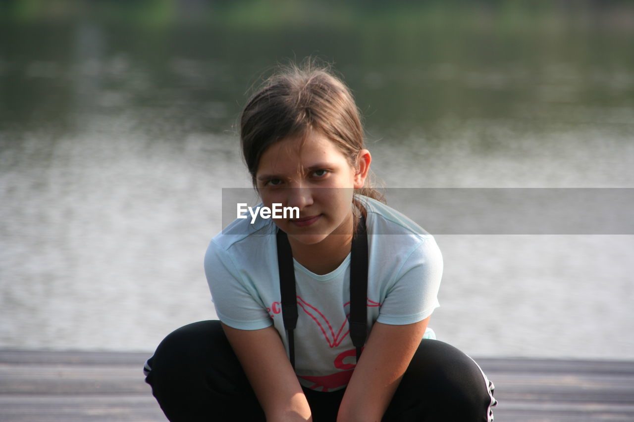 Portrait of girl crouching against lake