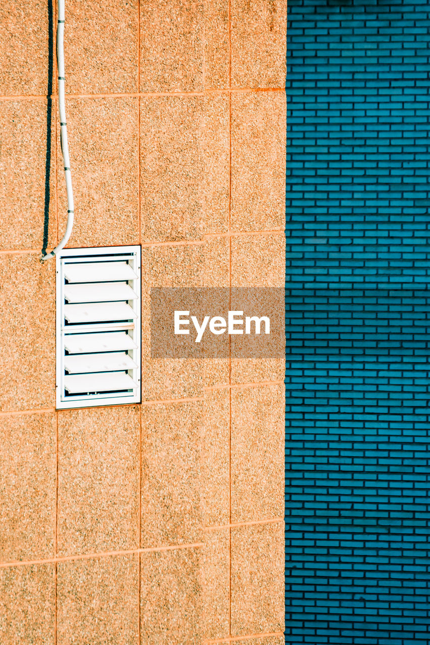 Full frame shot of blue bricks wall against window of building