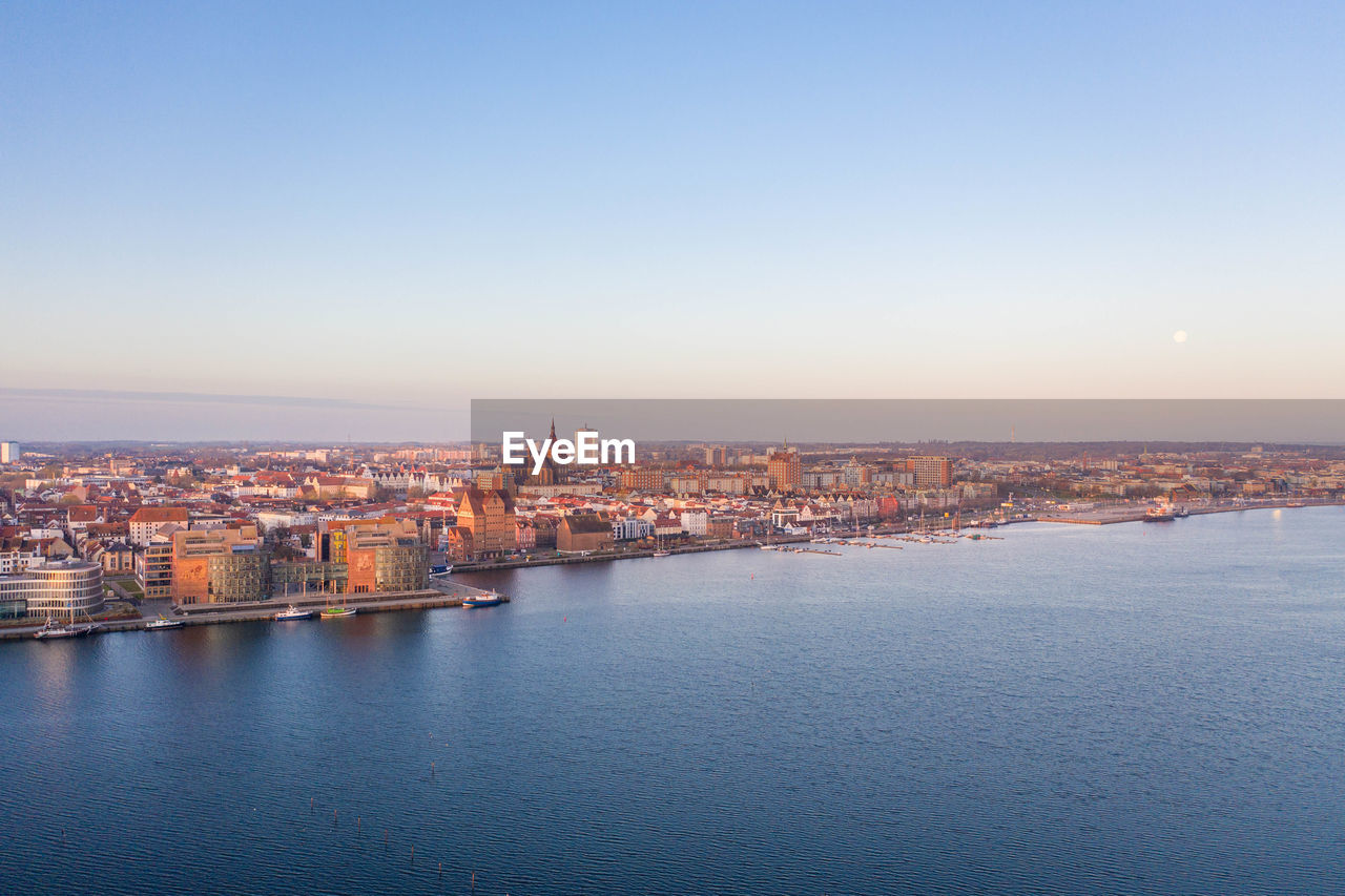 Scenic view of sea by buildings against sky at dusk