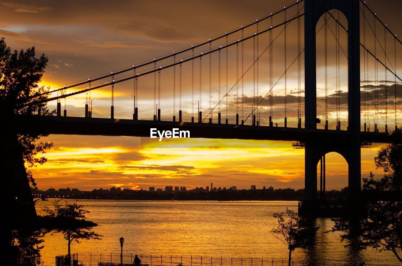 Low angle view of silhouette bronxwhitestone bridge over river during sunset