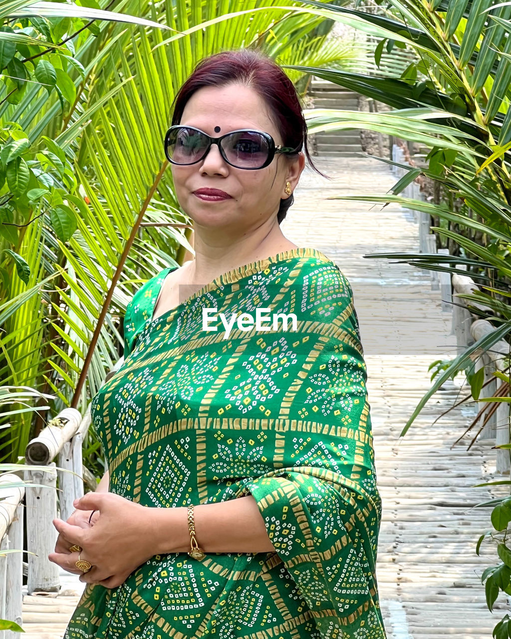 green, one person, glasses, adult, fashion, sunglasses, women, portrait, nature, young adult, standing, plant, clothing, looking at camera, dress, tropical climate, smiling, palm tree, photo shoot, leisure activity, day, outdoors, waist up, lifestyles, front view, three quarter length, water, growth, spring, jungle, female, casual clothing, tree, beauty in nature, hairstyle, sunlight, leaf