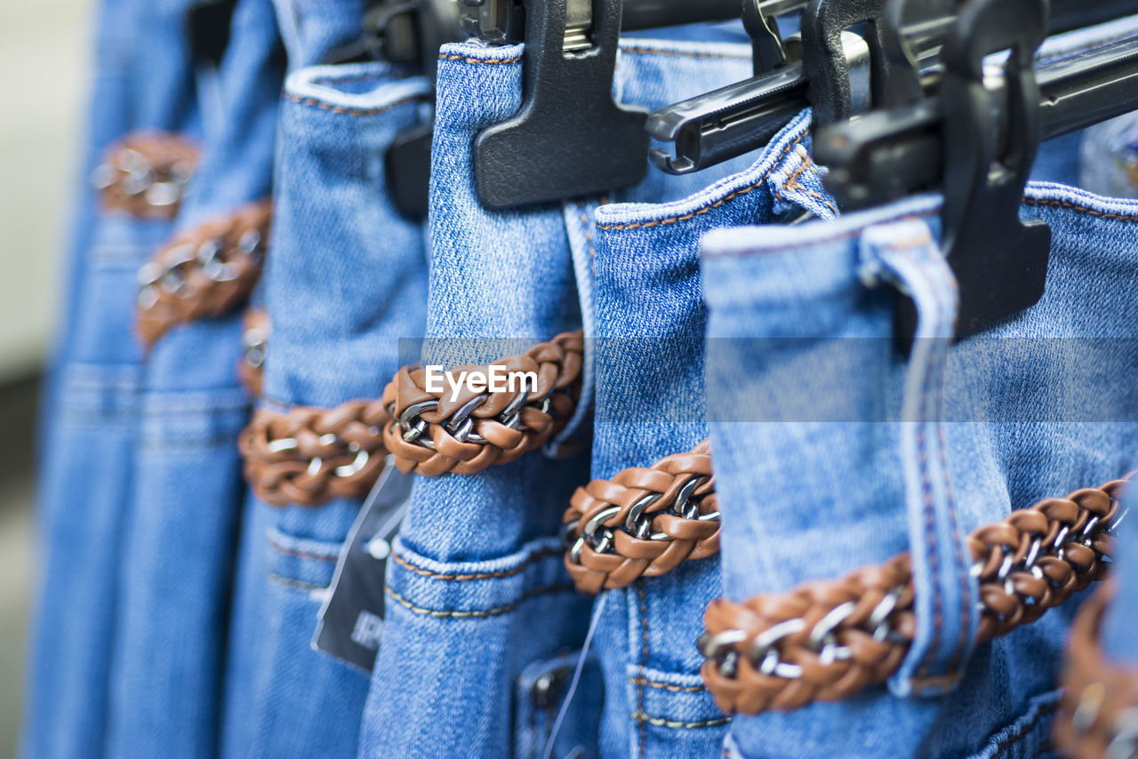 Jeans with belts on coathanger for sale in market