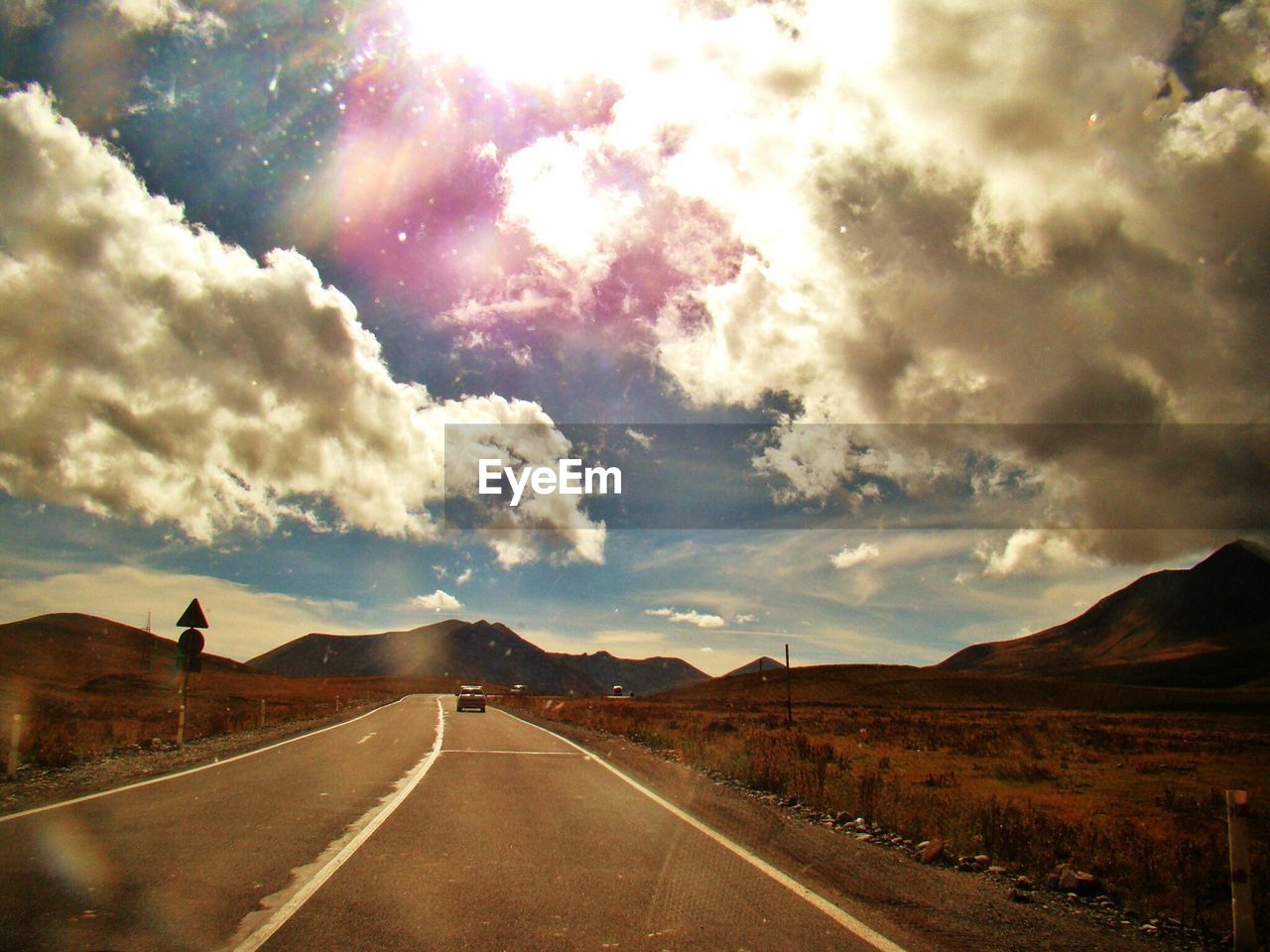 VIEW OF COUNTRY ROAD AGAINST CLOUDY SKY