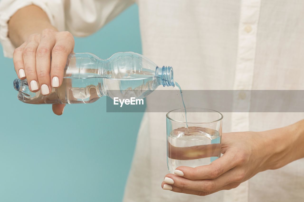 midsection of man pouring water in glass