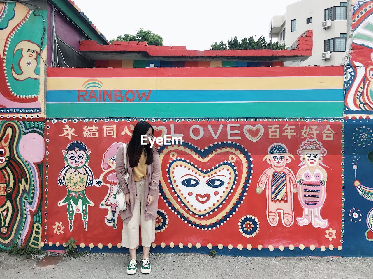 MIDSECTION OF WOMAN STANDING AGAINST GRAFFITI