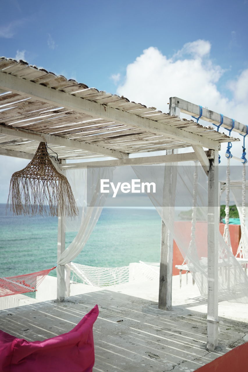 Lounge chairs by swimming pool at beach against sky