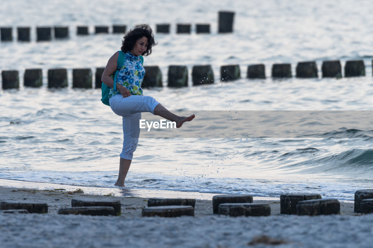 Full length of woman splashing on beach