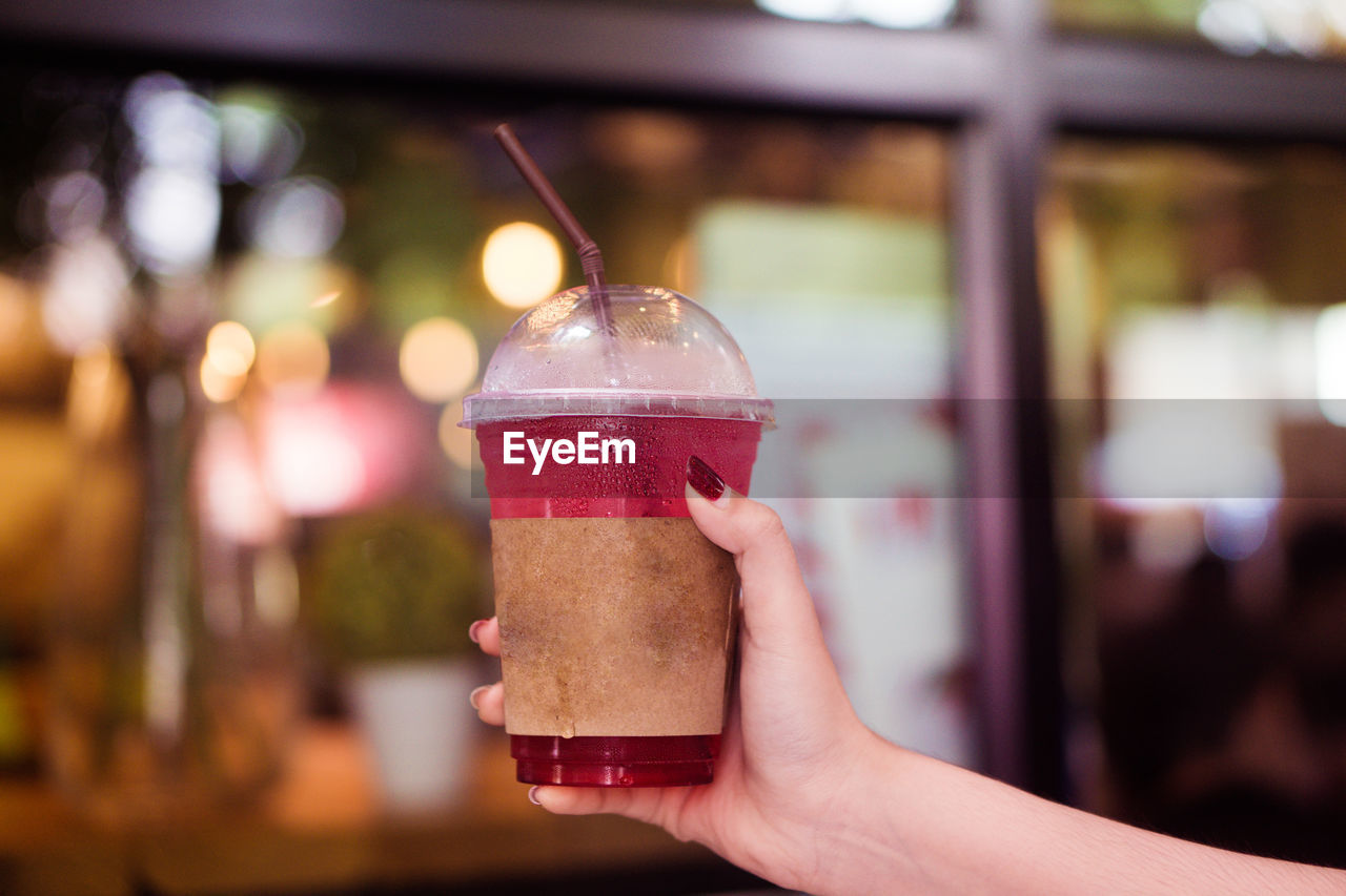 Cropped hand of person holding cold drink in city