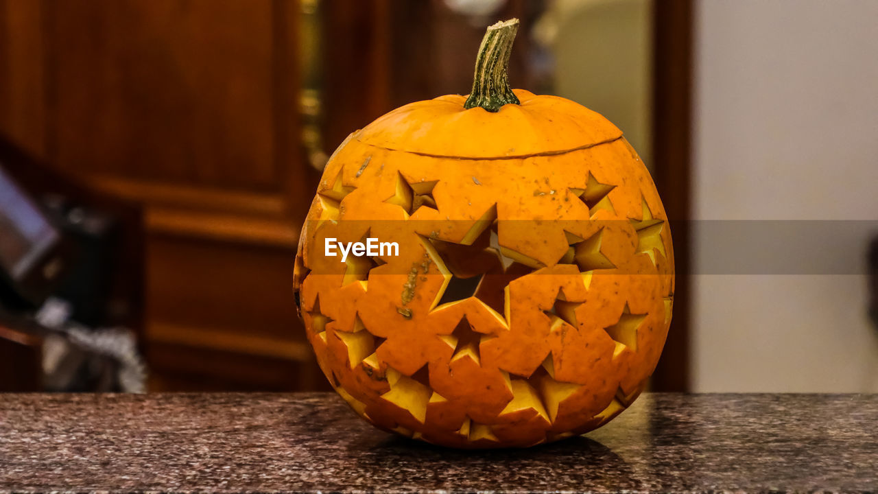 CLOSE-UP OF PUMPKIN ON TABLE AT HOME DURING HALLOWEEN