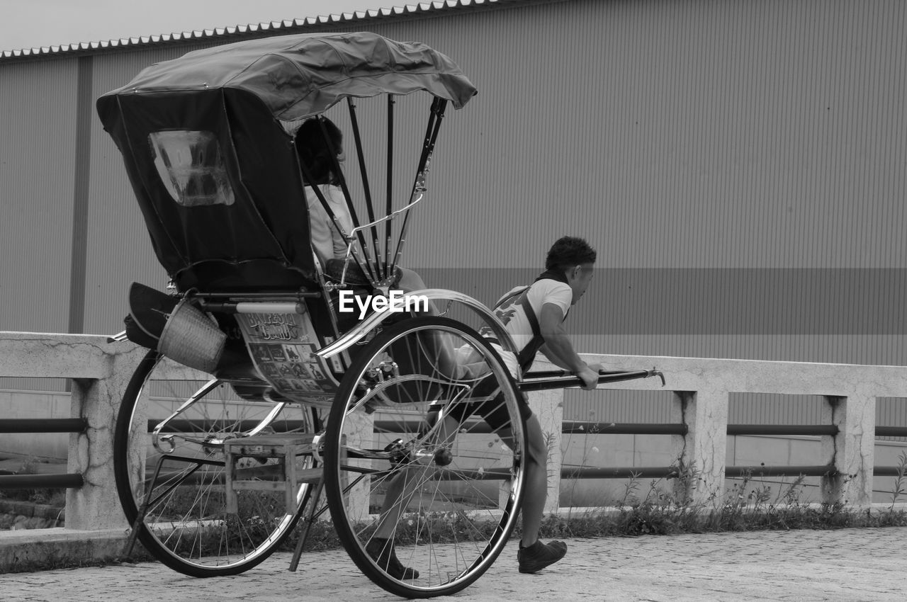 Man pulling woman sitting on cart