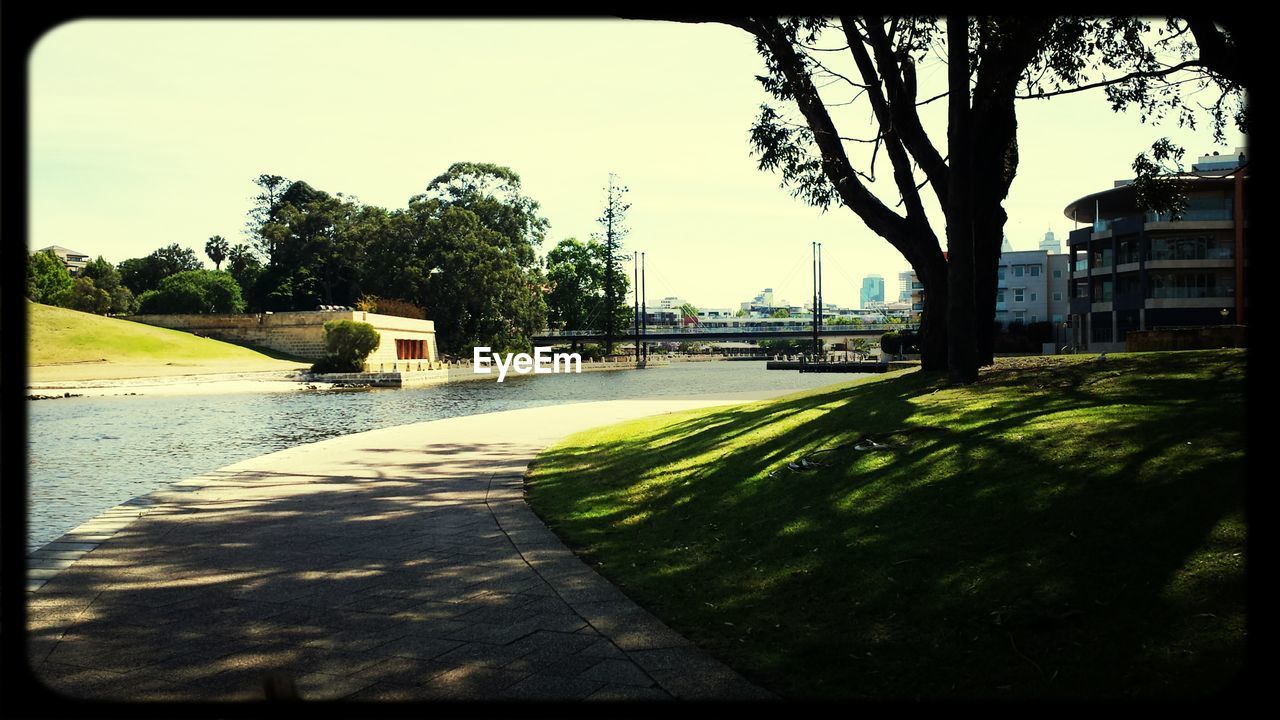 Walkway by lake against clear sky