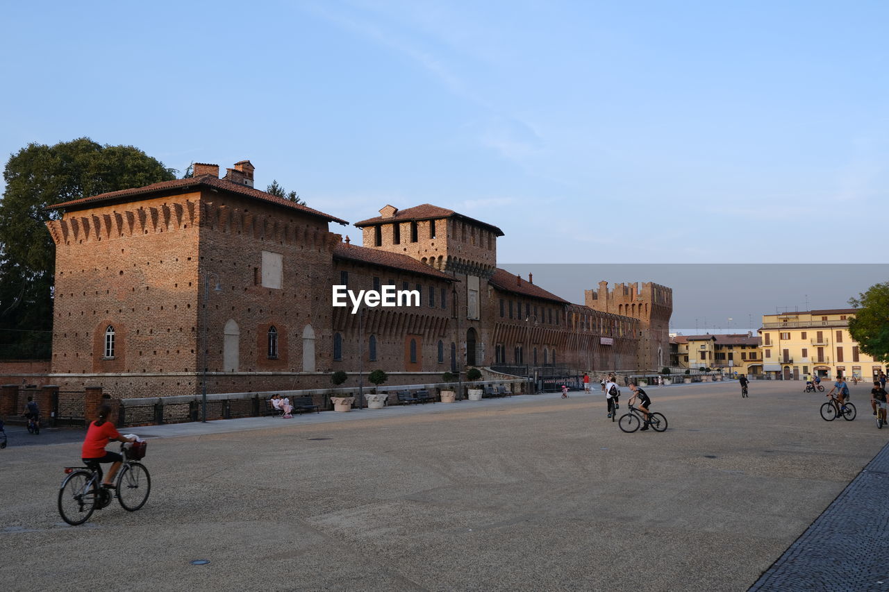 PEOPLE RIDING BICYCLE ON ROAD BY BUILDINGS IN CITY