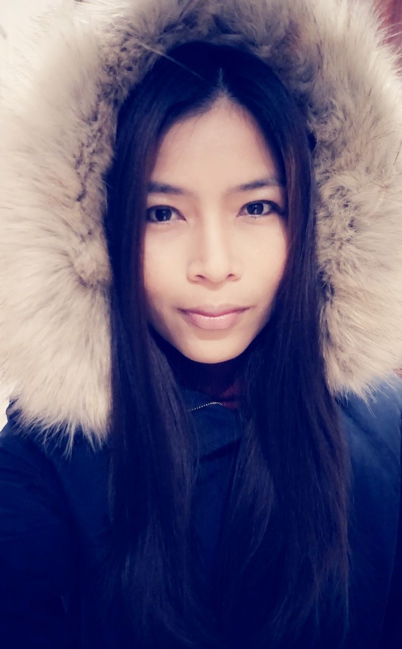 Close-up portrait of young woman wearing fur jacket