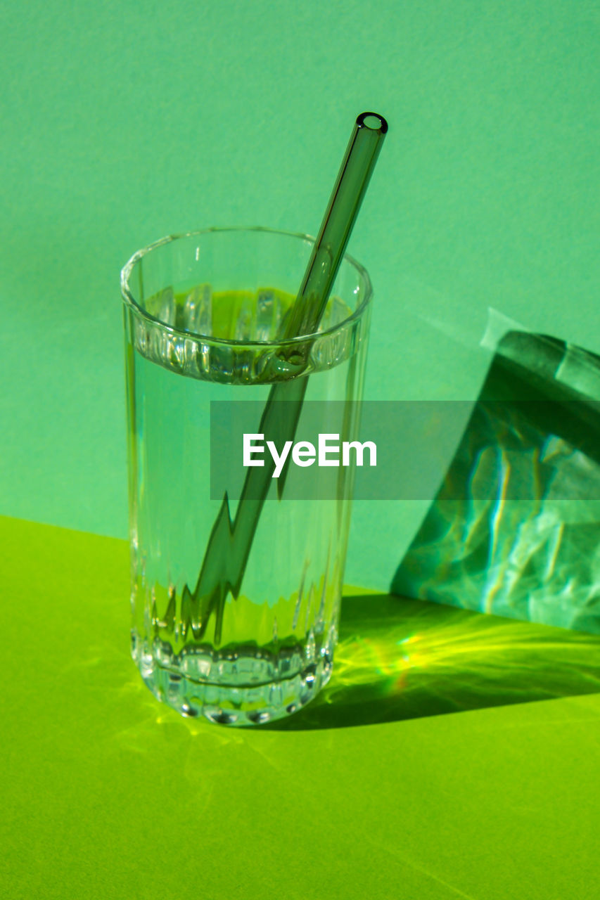 Reusable glass straws in glass with water on green background eco-friendly drinking straw set with