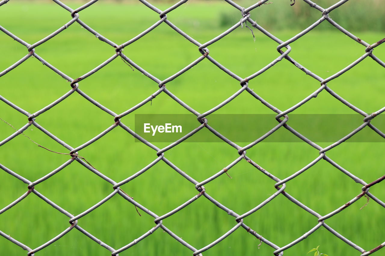 FULL FRAME SHOT OF CHAINLINK FENCE AGAINST THROUGH METAL GRATE