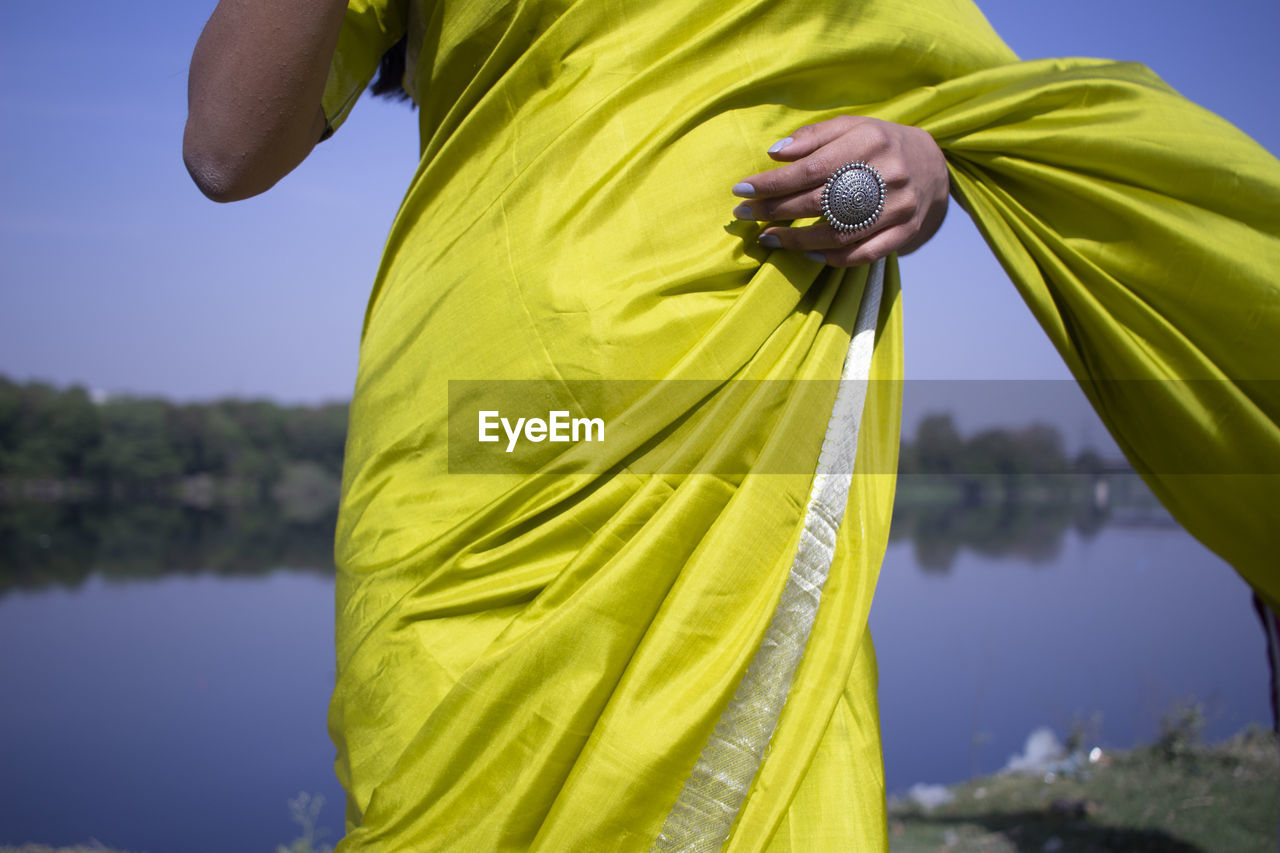 Midsection of woman wearing sari while standing by lake