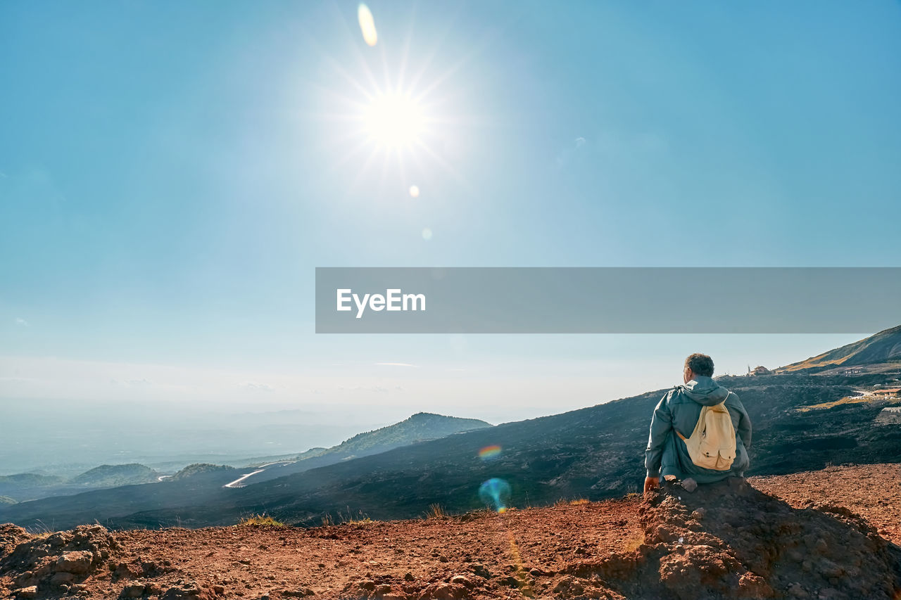 Mature man enjoying freedom, while admiring panoramic view of colorful summits of volcano etna