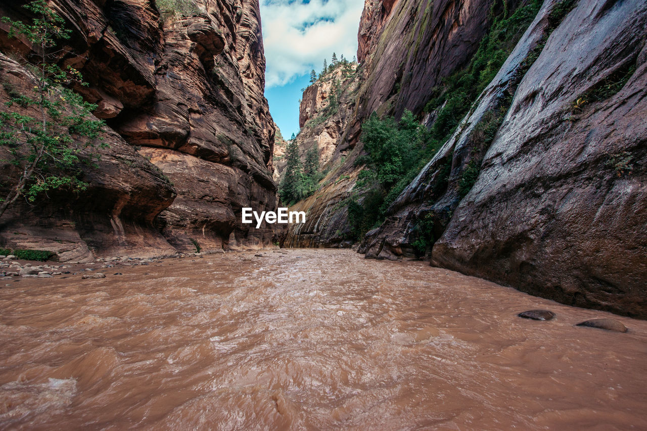 Scenic view of river flowing amidst rock formations against sky