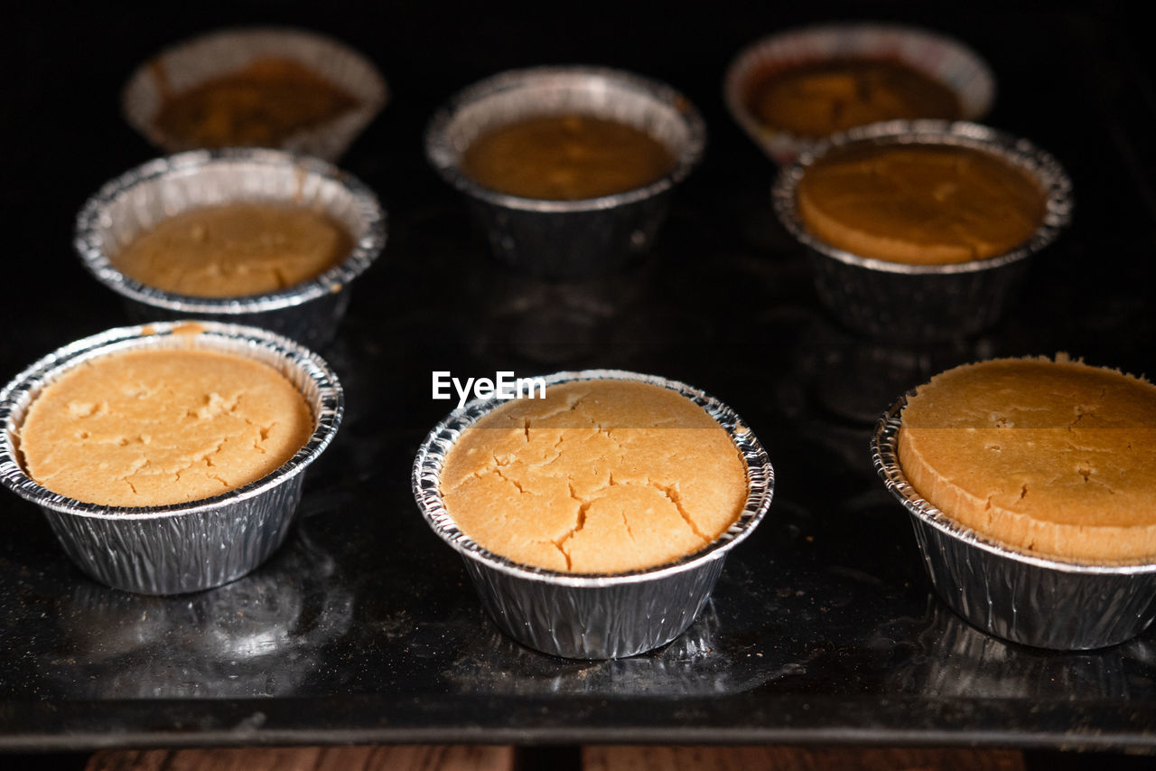 Cupcakes in tins stand in the oven, close-up