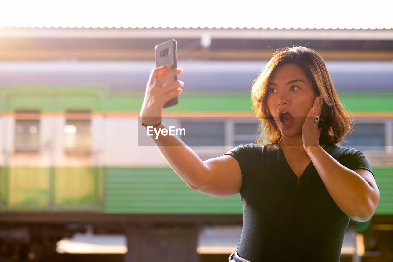 Portrait of young woman photographing through mobile phone