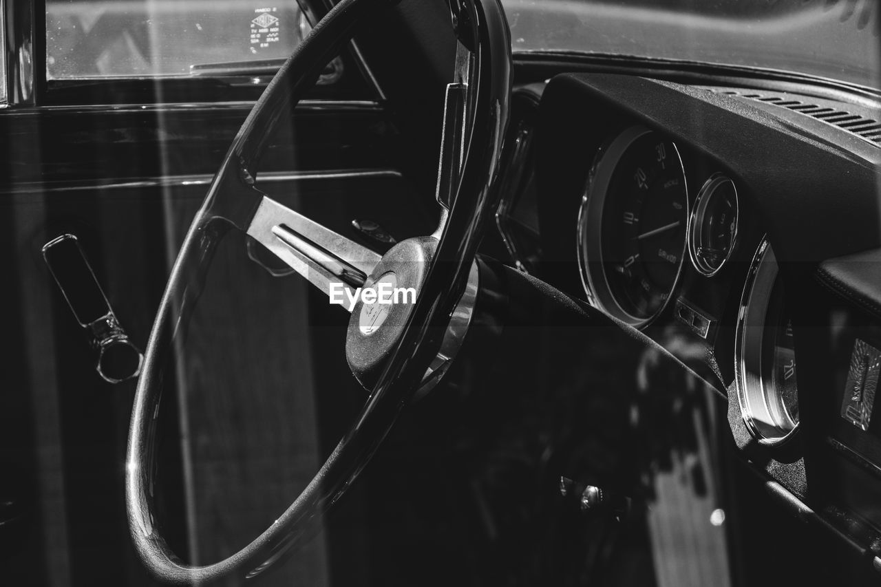 Steering wheel of vintage car seen from window glass