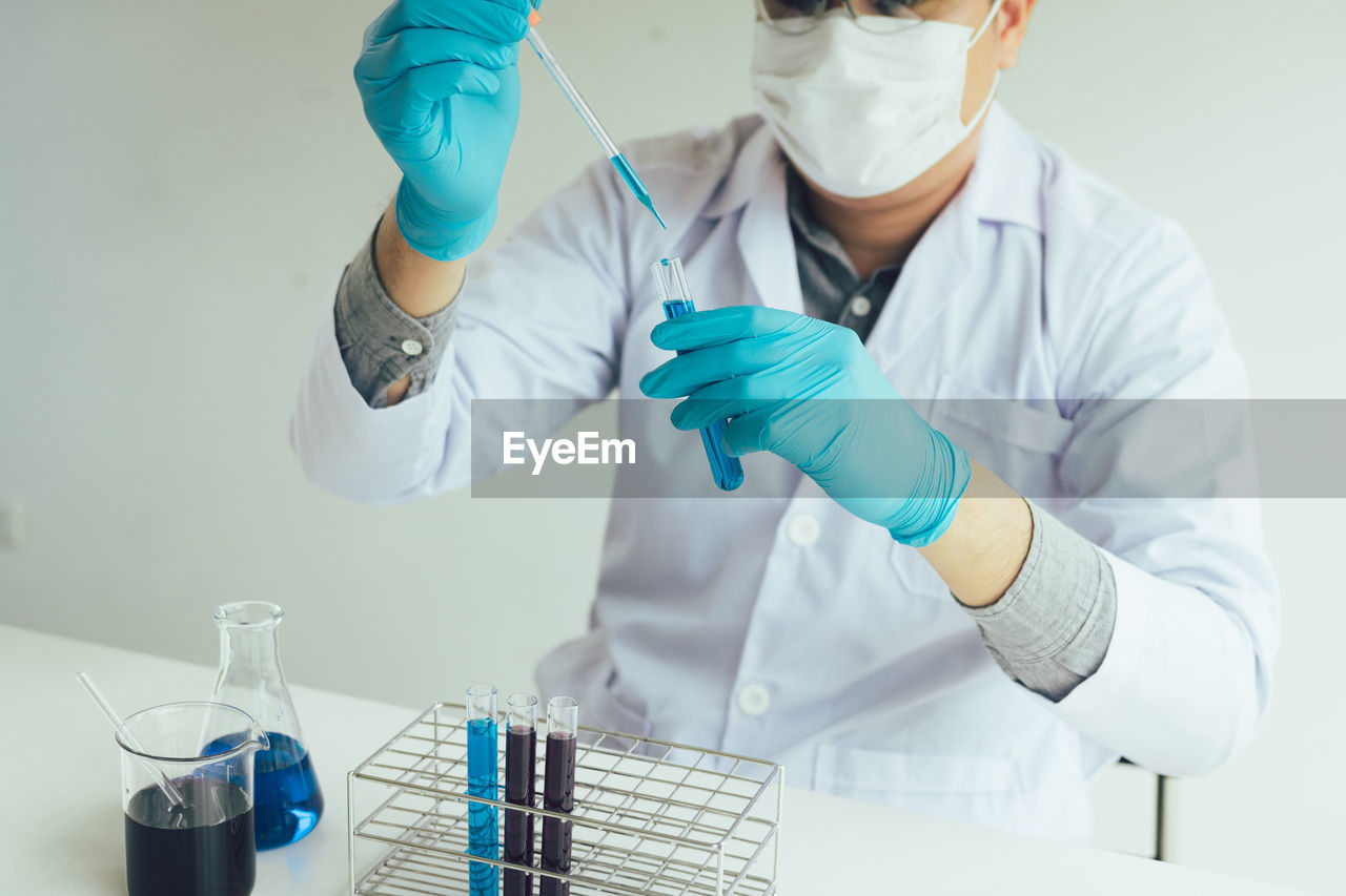 Midsection of scientist examining chemical in laboratory