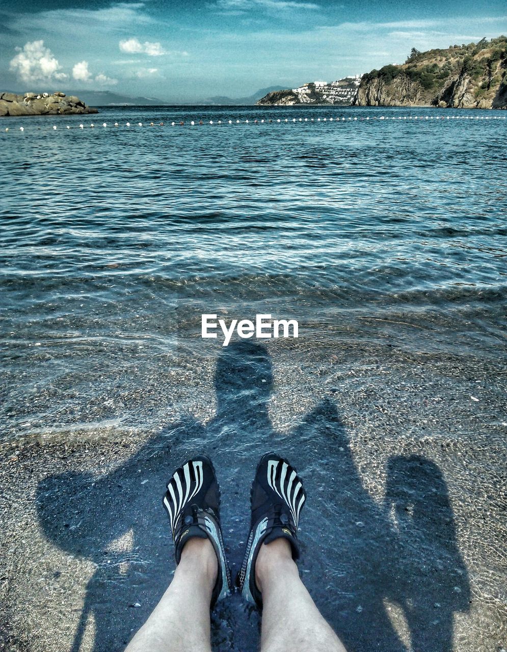 LOW SECTION OF WOMAN STANDING ON BEACH