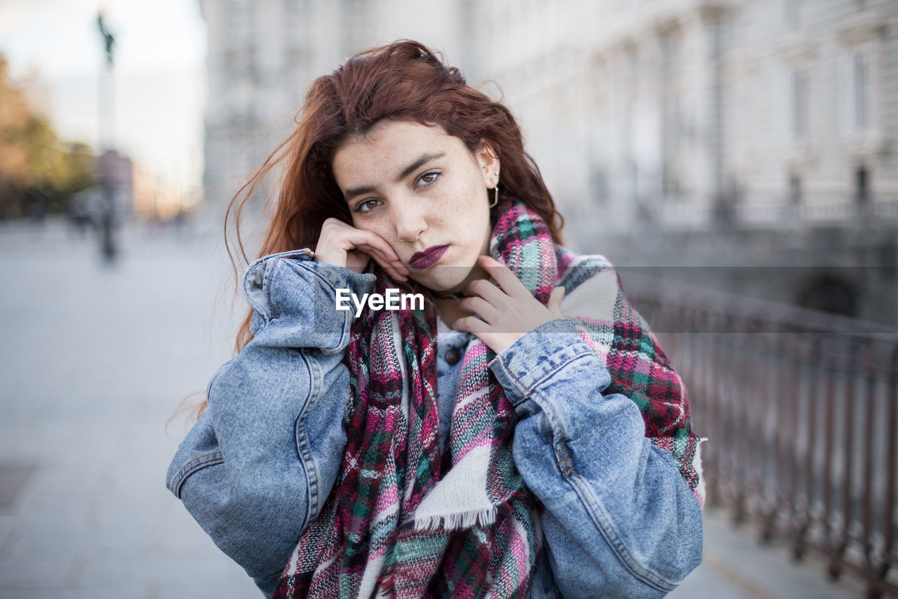 Portrait of woman in warm clothes while standing in city during winter