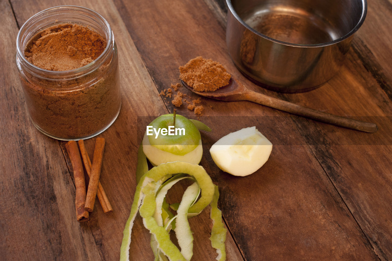 Fresh partly peeled apple, cinnamon sticks and powdered aromatic cinnamon spice in a spoon