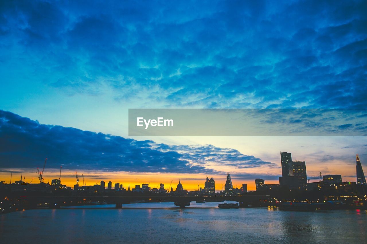 VIEW OF RIVER WITH CITYSCAPE IN BACKGROUND