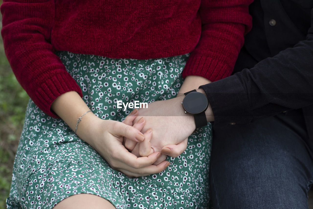 Midsection of couple holding hands