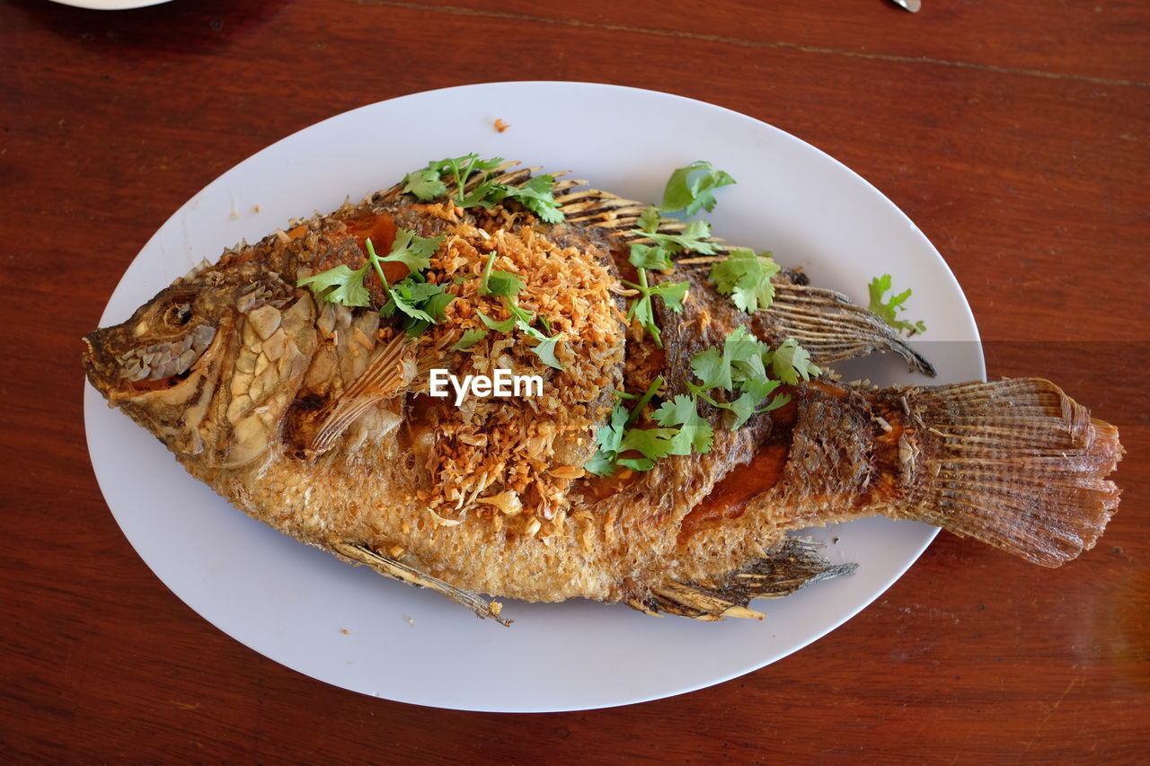 High angle view of fish in plate on wooden table