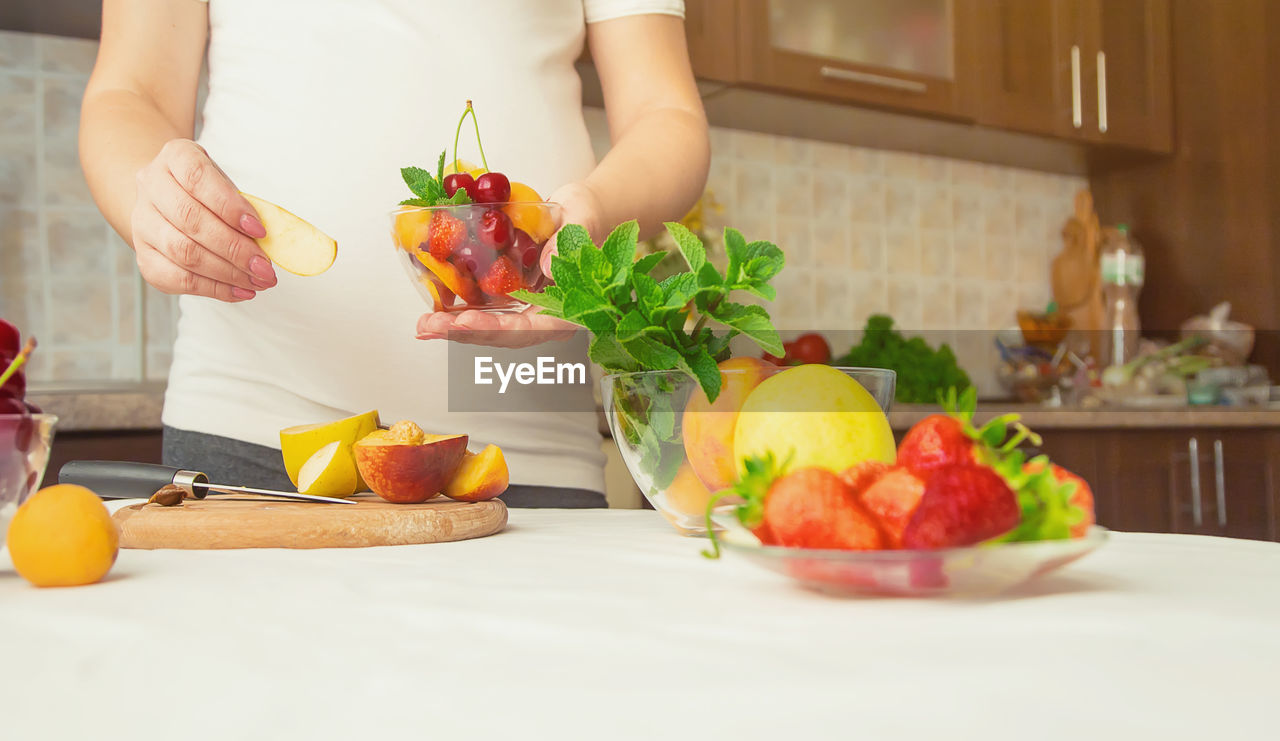 Midsection of woman holding fruits in bowl