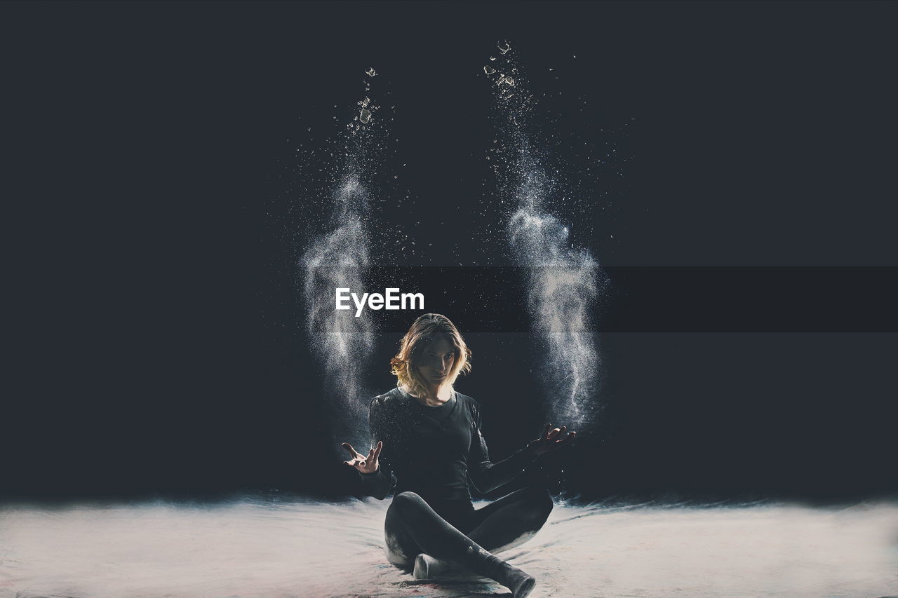 Creative portrait of young woman against black background