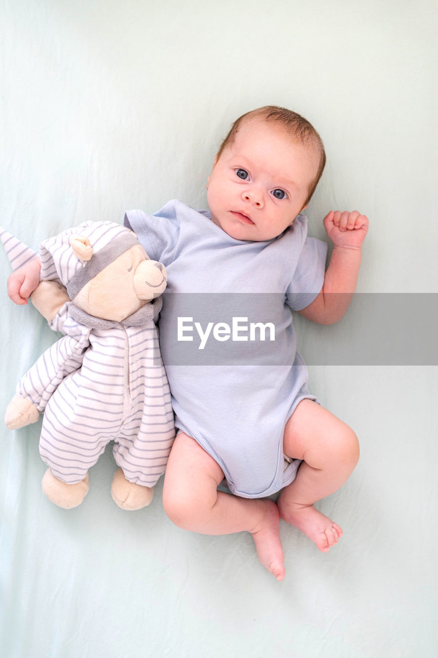 portrait of cute baby boy lying on bed at home