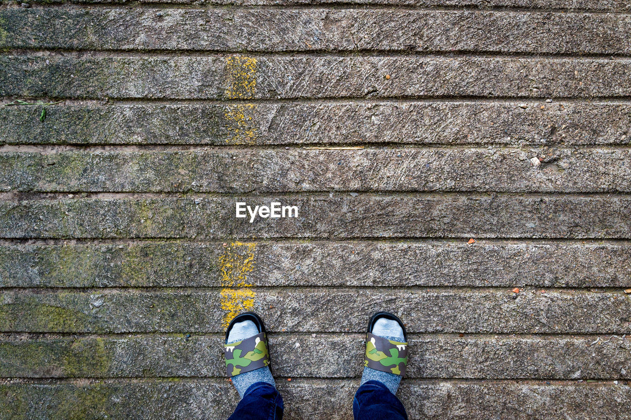 LOW SECTION OF MAN STANDING ON COBBLESTONE FOOTPATH