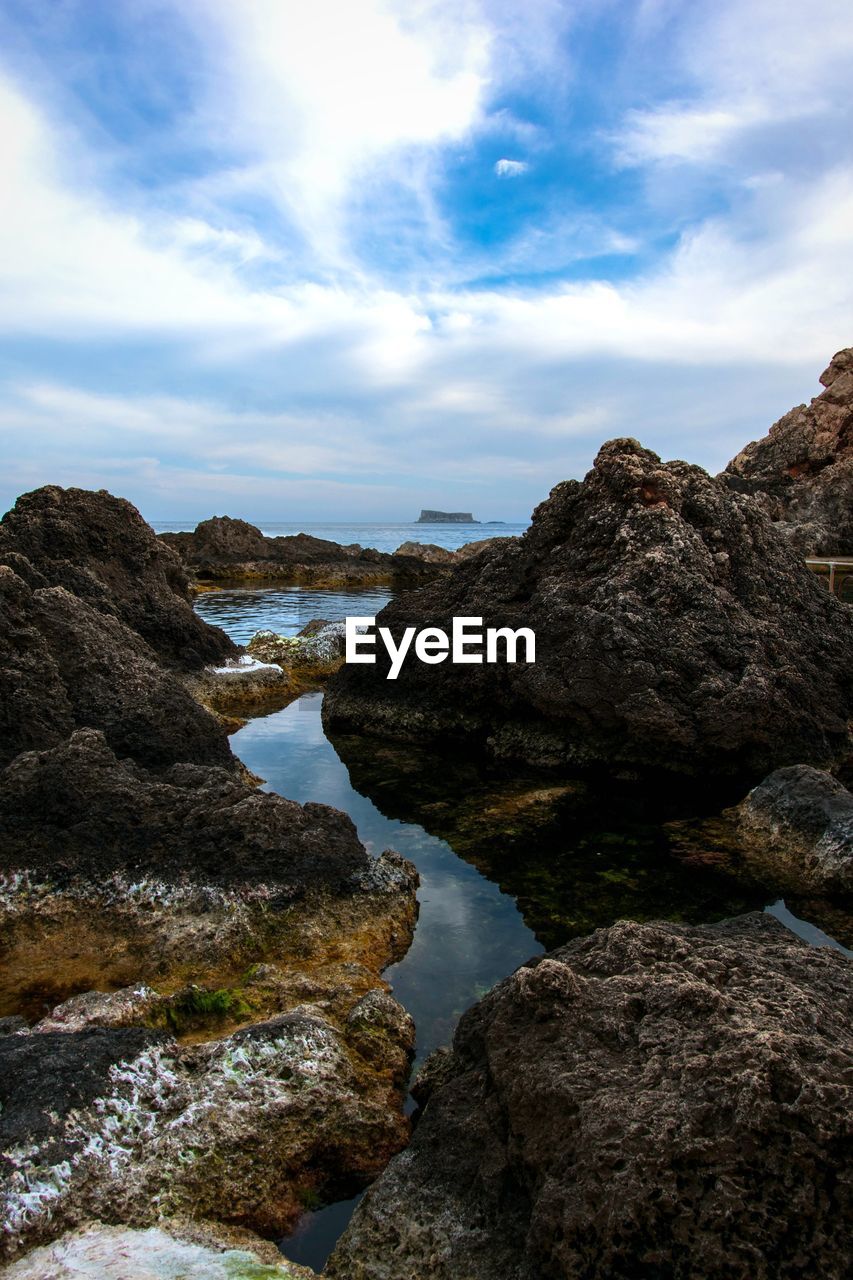 SCENIC VIEW OF ROCKS ON BEACH AGAINST SKY